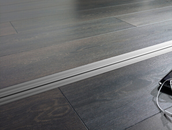 Smartphone with earphones on dark laminate flooring with a sleek design.